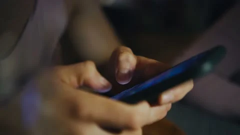 Message on his smartphone while sitting at a table in a cafe in the evening Stock Footage 168523120