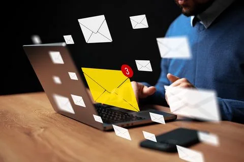 Message notifications appear on computer while a man works at a desk during Stock Photos