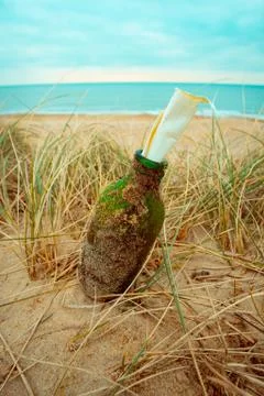 Message in a Sandy Bottle on a Grassy Beach with Sea Background Stock Photos
