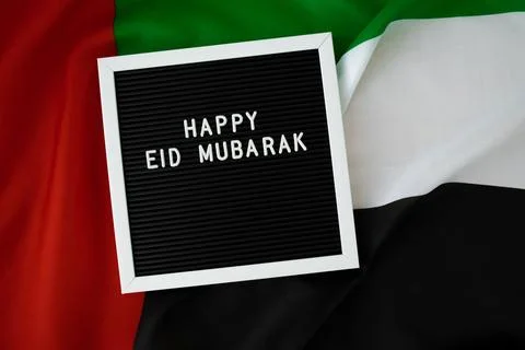 Message text HAPPY EID MUBARAK - happy holidays waving UAE flag on background Stock Photos