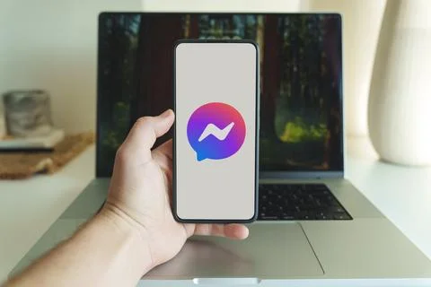 Messenger app logo on cellphone screen. Person holding facebook messenger Stock Photos