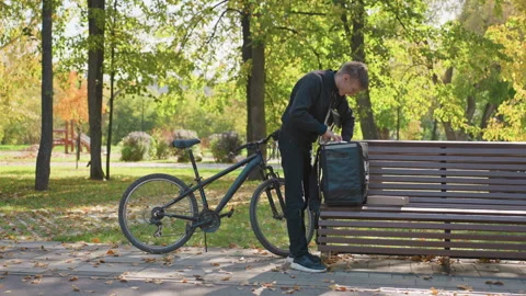 Messenger hands over parcel carefully, Couriers in urban parks exchange goods Stock Footage 331254095