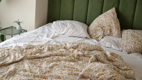 Messy bed with floral bedding in a home setting Stock Footage 340304253