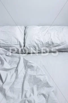 Messy bed with gray bedclothes Stock Photos