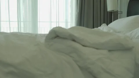 A messy bed with a white comforter and pillows Stock Footage 313371365