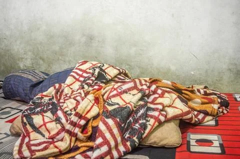 Messy bedroom featuring a patterned blanket and pillow on an unmade bed, se.. Stock-Fotos