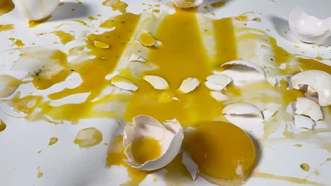 Messy broken eggs and egg shells on white seamless background Stock Footage 304232881