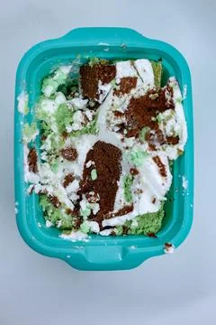 Messy cake leftovers inside a turquoise plastic container Stock Photos