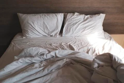 Messy comfy white bed sheets and pillow life on Holiday . untidy unmade bed w Stock Photos