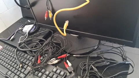 Messy computer cables on a desk. Tangled electronic wires and PC hardware setup. Foto stock