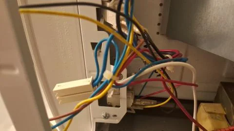 Messy electrical wires connected inside a white plastic appliance housing Stock Photos