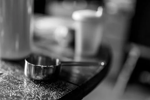 Messy kitchen table top with measuring cup and granules of sugar Stock Photos