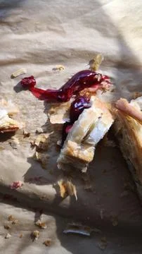 Messy leftover cherry pastry with flaky crumbs on parchment paper. Stock Photos