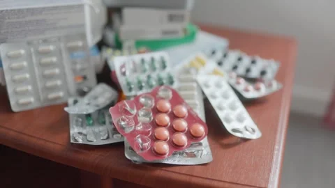A messy pile of different medication blisters on a wooden nightstand. Stock Footage 336662484