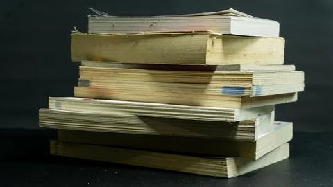 Messy stack of books with uneven alignment against black background, disorg.. Stock Photos