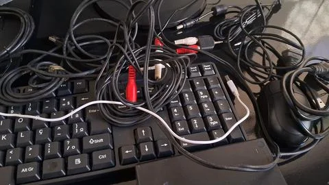 Messy tangled computer cables on desk. Disorganized tech wires creating Stockfoto's