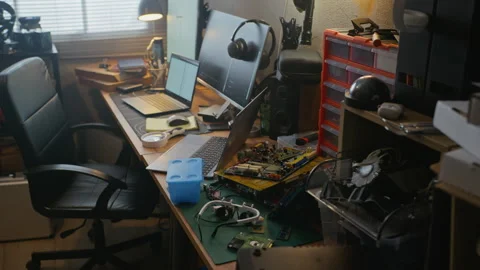 Messy Tech Workspace Displaying Computer Hardware with Monitors Stockbeeldmateriaal 338421546