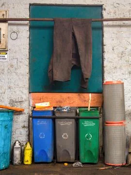 A messy trash corner in a car workshop with three plastic bins labeled in Spa Foto stock