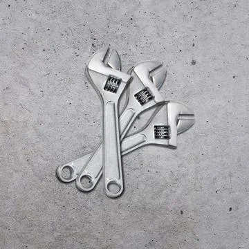 Metal adjustable wrenches on a cement background, top view Stock Photos