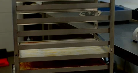 Metal bakery rack with mostly empty shelves and single tray in commercial Stock Footage 344582968