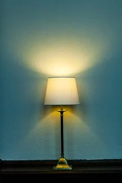 Metal base table lamp lighted lying wooden furniture. Luminous stand chand... Stock Photos