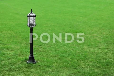 Metal black street lamp on green grass Stock Photos