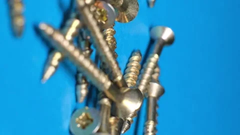 Metal bolts falling on a blue background in slow motion. Vertical video Stock Footage 250111615