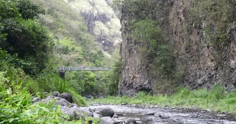 Metal bridge between two big mountains over wild river Stock Footage 83856211