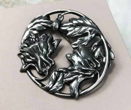 Metal brooch with a pattern on a white background, close-up Stock Photos