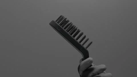 Metal brush in hand on a gray background. Video stock 265597053