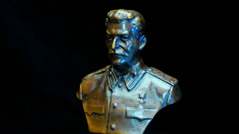 Metal bust of the head of the Soviet state Joseph Stalin rotates on a black back Stock Footage 120731082