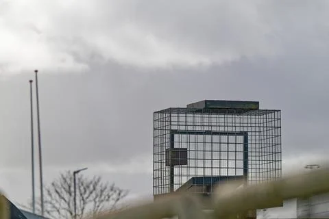 Metal cage structure against cloudy sky with blurred foreground elements Stock Photos