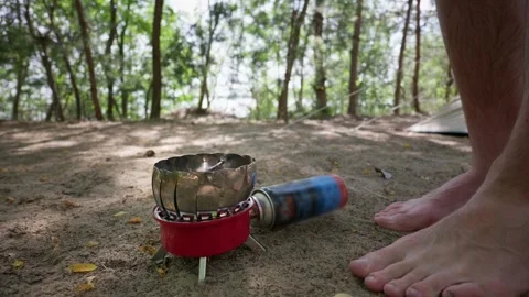 Metal Camping Mug Heating on Portable Gas Stove at Forest Campsite Stock Footage 341994368