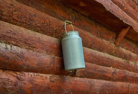 An metal can hangs from a nail driven into the wall of a log house Stock Photos