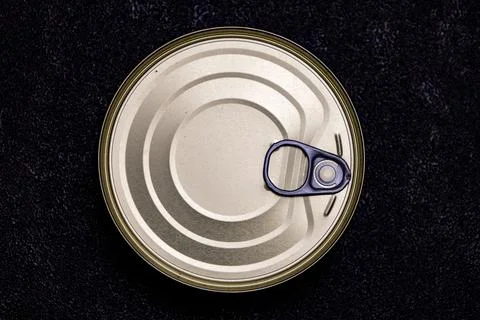 Metal can top with pull tab and curved patterns placed on a black surface Stock Photos
