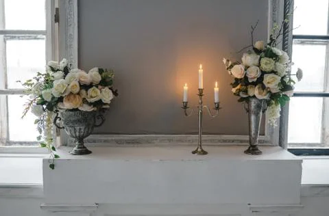 Metal candle holder with burning candles and vases with artificial flowers on Stock Photos