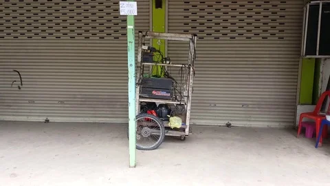 Metal cart with electronics and cables on street, note on pole, Vientiane, Laos 스톡 동영상 75821858