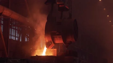 Metal casting process. Pouring bright molten liquid metal into mold with flying Stock Footage 154321834