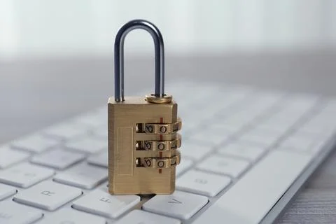 Metal code padlock and computer keyboard on table, closeup. Cyber security co Stockfoto's