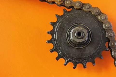 Metal cogwheel and chain on orange background. Foto stock