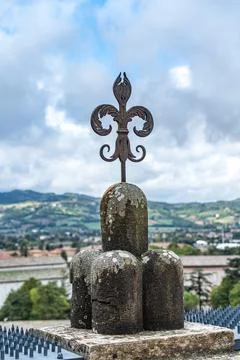 A metal cross is on top of a stone wall in Gubbio Italy Umbria Palazzo dei .. Stock Photos