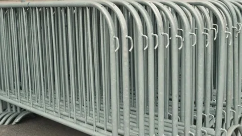 Metal crowd control barriers are lined up neatly in a public area, preparing for Video stock 339094322