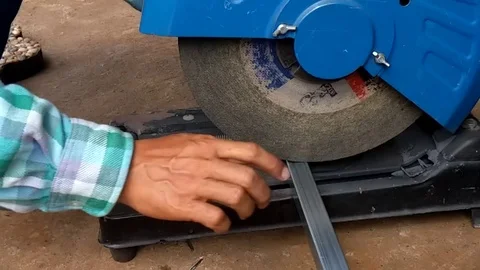 Metal cutting saw cuts a thin square tube, orange sparks from metal cutting saw. Stock Footage 115764282