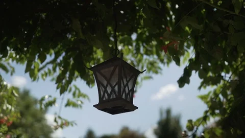 Metal dark brown lantern sways in the wind in the garden on a summer day Stock Footage 129085530