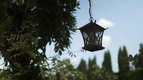 Metal dark brown lantern sways in the wind in the garden on a summer day Stock Footage 129085553