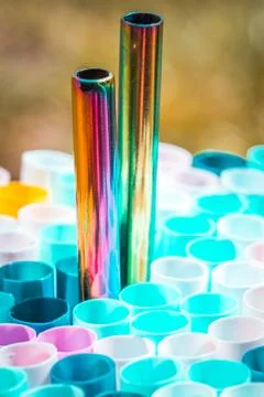 Metal drinking straw between othe ordinary plastich ones. Ecology zero waste Stock Photos