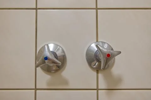 Metal Faucet Knobs on Tiled Wall Stock Photos