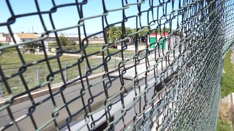 Metal fence behind which a train passes in slow motion Stock Footage 172217306