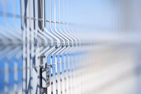 The metal fence is large against the background of the river, the sky with a Stock Photos