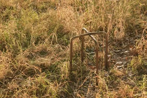 Metal frame of an old stool rusty in the meadow at sunset Foto stock